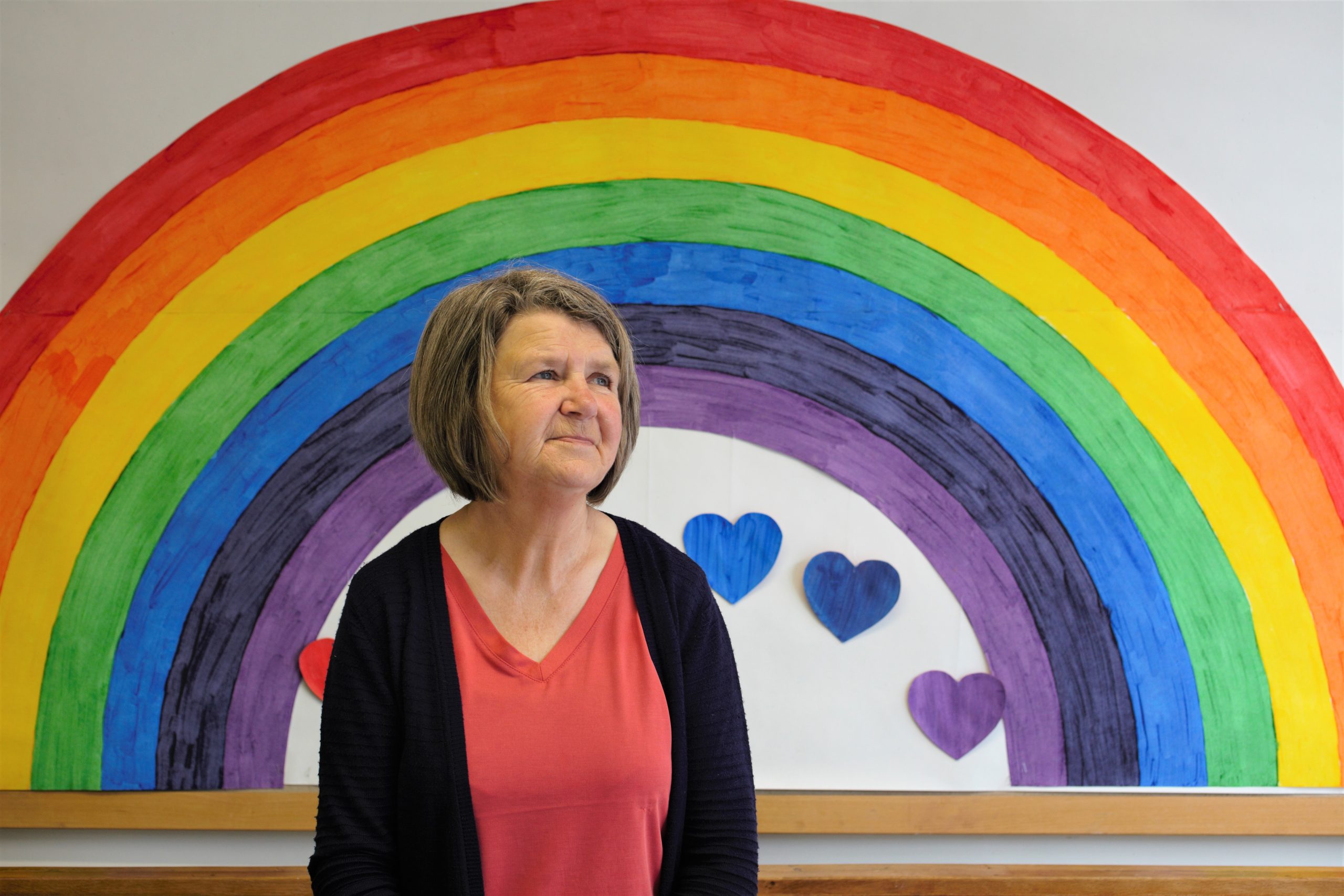 Woman standing infront of a rainbow painting