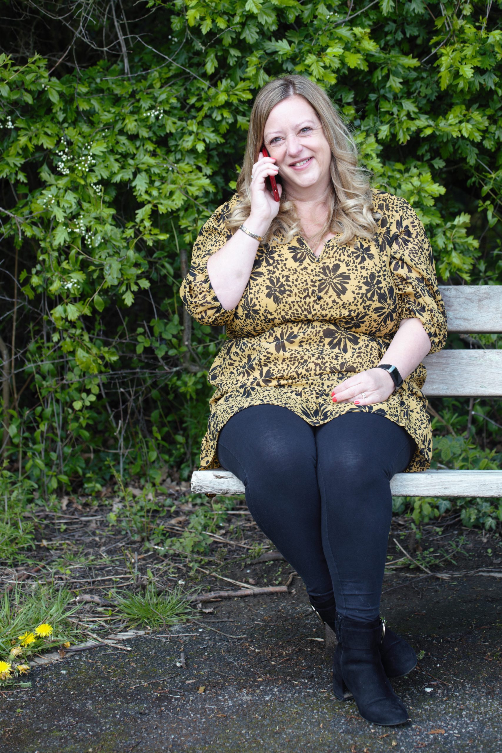 Woman on a mobile phone sitting on a bench smiling