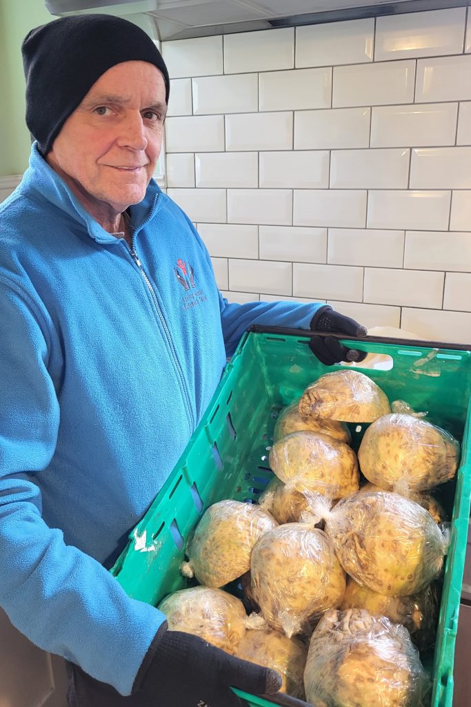 Photo of volunteer Chris with tray of vegetables