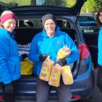 photo of 3 volunteers unpacking loaves of bread from car.